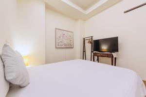 ein weißes Schlafzimmer mit einem Bett und einem Fernseher in der Unterkunft 花蓮密絲朵包棟民宿 4-14人 l 近花蓮火車站 l 電動麻將桌 in Hualien