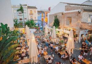 a crowd of people sitting at tables in a street with umbrellas at Poseidon Denia in Denia