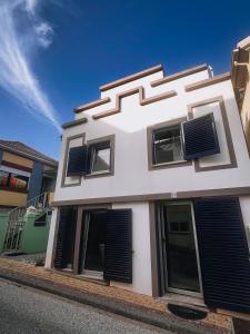 un edificio blanco con persianas negras. en Casinha Praia Azul, en Costa de Lavos