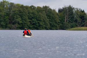 two people are rowing a boat on a lake at Gut Groß Zecher - Ferienzimmer in Seedorf