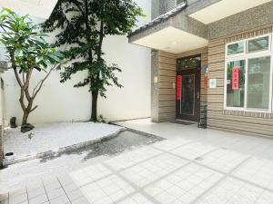 ein Haus mit einem Baum vor einer Tür in der Unterkunft 花蓮密絲朵包棟民宿 4-14人 l 近花蓮火車站 l 電動麻將桌 in Hualien