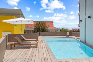 a swimming pool with a chair and an umbrella at The Wharf apartments, downtown Willemstad in Willemstad