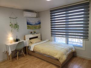 a bedroom with a bed and a desk and a window at Incheon Intl Airport ANN Guest House in Incheon