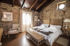 a bedroom with a bed and a chair and a window at Hotel Rustico Lugar Do Cotariño in Camariñas