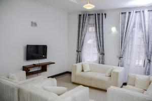 a living room with white furniture and a flat screen tv at Comfortable and Spacious house in Arusha