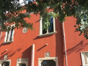 a red building with two windows and a tree at Villa Astoria in Taormina