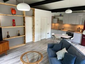 a living room with a blue couch and a kitchen at Richmond Hill Cottage Markington in Ingerthorpe