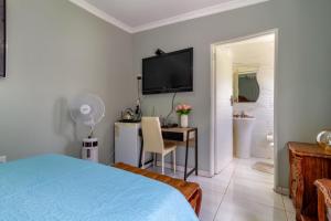 a bedroom with a bed and a desk and a television at Smuthaven in Krugersdorp