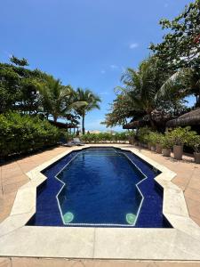a swimming pool with blue water and palm trees at Casa Mar Arraial d'Ajuda in Arraial d'Ajuda