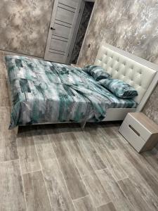 a bedroom with a white bed and a wooden floor at Двухкомнатная уютная квартира in Ekibastuz