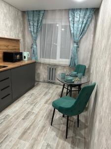 a dining room with a table and green chairs at Двухкомнатная уютная квартира in Ekibastuz