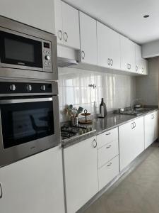 a kitchen with white cabinets and a microwave at Fanon Flat T2 in Mindelo