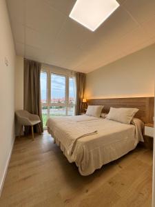 a bedroom with a large bed and a large window at Apartamentos Villa Alemar Playa De Somo in Somo