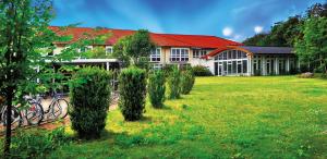 a building with a row of bushes in a yard at Landsitz Hotel Templin in Templin