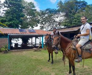 two men riding on horses in a yard at Hostel Los Chocoyos in Ometepe