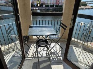 una mesa y un taburete en un balcón con vistas al agua en Studio chaleureux avec piscine, en Le Barcarès