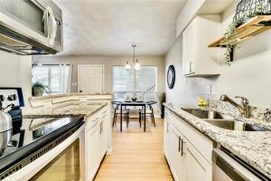 a kitchen with white cabinets and a dining room with a table at Global Cup Insta-Worthy Flat and Arboretum Tickets Included in Dallas