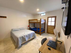 a bedroom with a bed and a desk with a computer at Casa Kahuna in Canoas de Punta Sal
