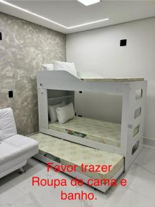a white bunk bed in a room with a couch at BARRAVENTO RESIDENCE - RIVIERA SÃO LOURENçO in Bertioga