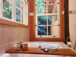 Un baño con bañera con dos ventanas. en Refúgio Terracota uma casa bioconstruída com arte, en Mairiporã