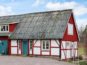 a red and white barn with a gray roof at 4 star holiday home in MUNKA-LJUNGBY in Munka-Ljungby