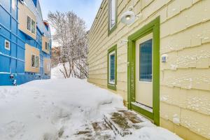Un montón de nieve junto a un edificio con una puerta verde. en Near Hiking Cozy Anchorage Retreat with Fireplace!, en Anchorage