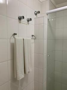 a shower with two white towels and a glass door at Lory Studio Hotel in São Paulo