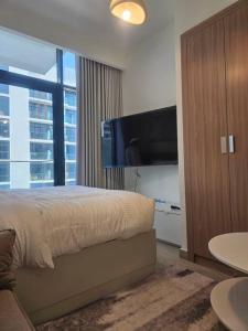 une chambre avec un lit et une télévision à écran plat dans l'établissement Luxury Studio near burj khalifa in Azizi Riviera, à Dubaï 24 autres photos