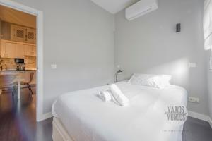 a white bedroom with a large white bed with white pillows at Sutil elegancia para 3, en Plaza de Chueca in Madrid