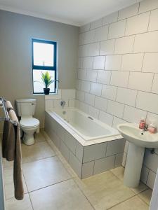 a bathroom with a tub and a toilet and a sink at Homely Stay in Kempton Park +20 photos
