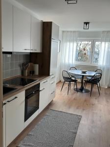a kitchen with white cabinets and a table with chairs at Familienfreundliche FEWO in bester Lage in Offenburg +8 photos