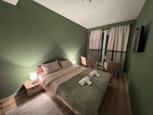 a green bedroom with a bed with two towels on it at Sky Lux Point in Skopje +21 photos
