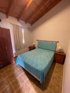 una camera da letto con un letto con un piumone blu di Costa magica a Las Grutas