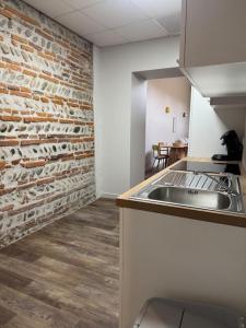 a kitchen with a brick wall and a sink at Logement T3 centre-ville in Muret