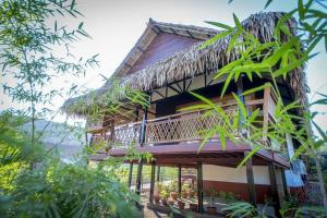 a house with a thatch roof and a balcony at Hotel Queen Jamadevi in Mawlamyine