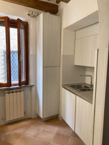 uma cozinha com armários brancos, uma pia e uma janela em Marconi La Casetta em Panicale