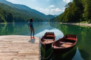 a woman standing on a dock with two boats on a lake at Modern Harmony in Kolašin