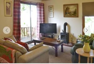 a living room with a couch and a table and a television at Rowan Cottage, NC500 in Greenland