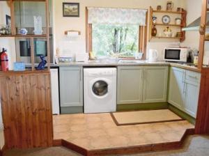a kitchen with a washing machine and a microwave at Rowan Cottage, NC500 in Greenland
