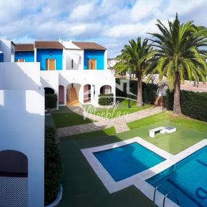 a villa with a swimming pool and palm trees at SeS ORENETES in Cala en Blanes