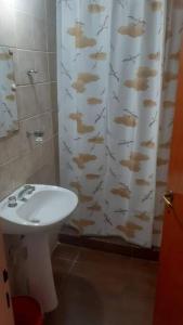 a bathroom with a sink and a shower curtain with fish on it at departamento por día ruta 41 2 in Los Antiguos