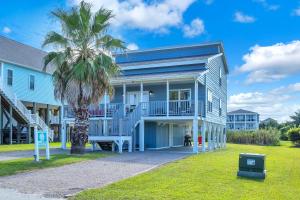 a house with a palm tree in front of it at SeaSide by Oak Island Accommodations in Oak Island