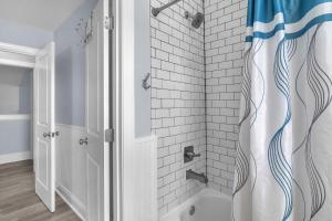 a bathroom with a shower with a blue and white shower curtain at SeaSide by Oak Island Accommodations in Oak Island +108 photos