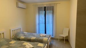 a bedroom with two beds and a window and a chair at Drazn vrt in Kotor