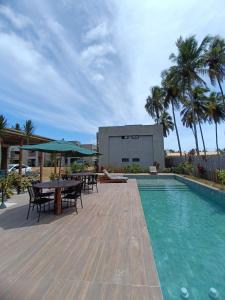 a pool with tables and chairs next to a building at Villas Patacho G 102 - Milagres in Pôrto de Pedras