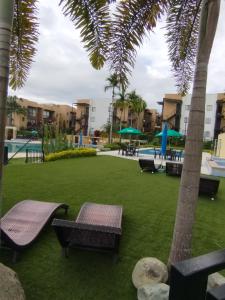 a resort with a pool and palm trees and benches at Descanso cafetero apartasol Tebaida in La Tebaida