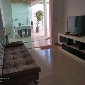 Una sala de estar con un sofá y un televisor de pantalla plana. en Casa de praia meu bom, en Rio das Ostras