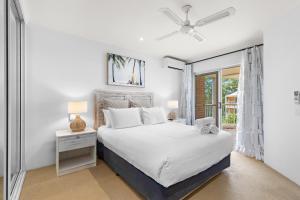 a white bedroom with a bed and a window at Serenity Apartments Noosa in Noosa Heads
