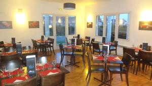 a dining room with tables and chairs and windows at Logis Hôtel & Restaurant & Bar LE COTTAGE in Calais
