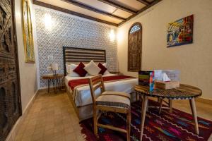 a bedroom with a bed and a table with a chair at Riad Nalan & Spa in Marrakech
